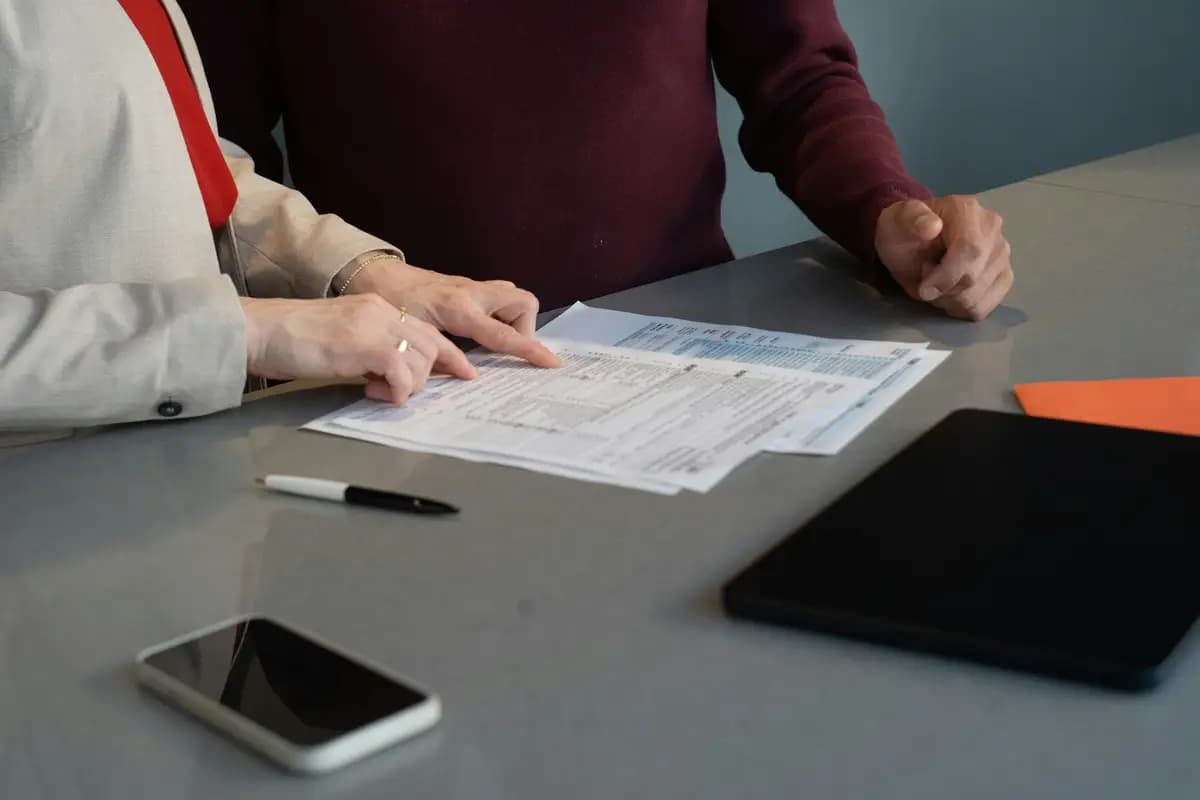 Doi colegi verifică documentele unei licitații la masă
